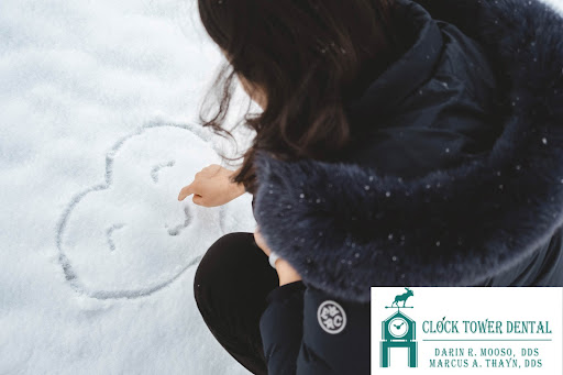 Person drawing a smile in a heart in the snow.